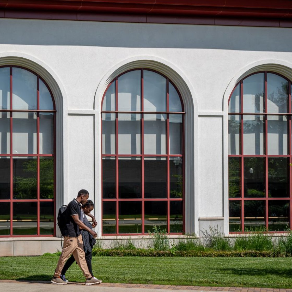 Two students walk through campus with ones arm around another.