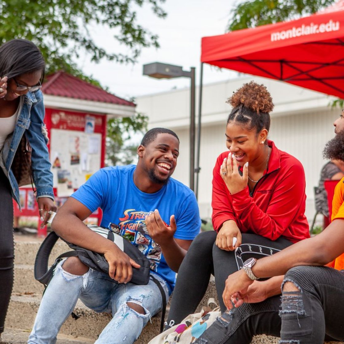 Four students are together, laughing and smiling with one another.