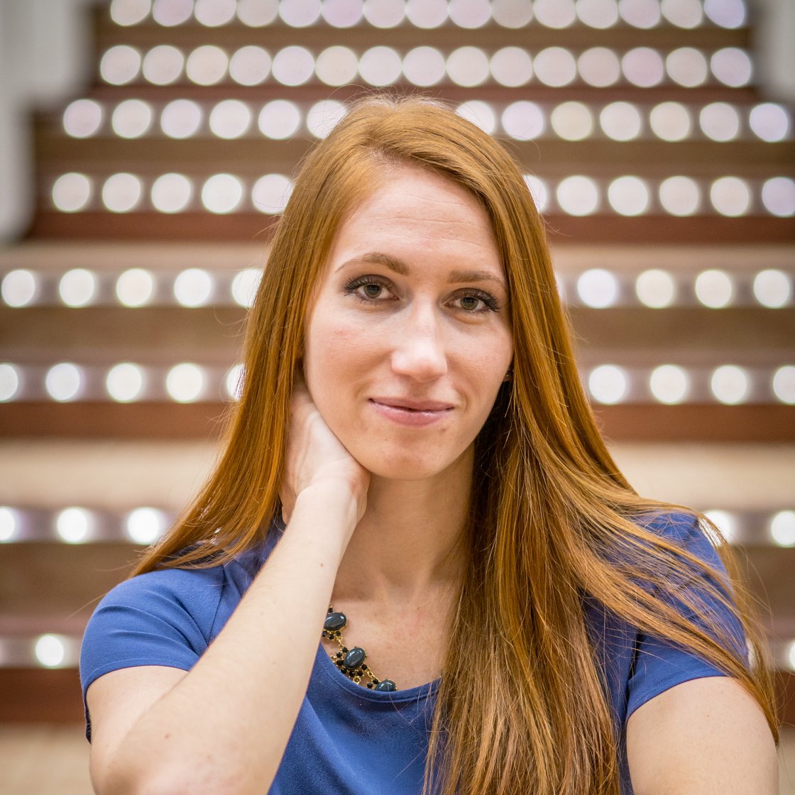 Female student smiling with red hair sitting on steps.
