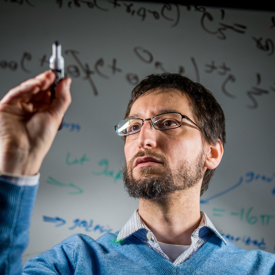 Man is writing on a white board with a black marker.