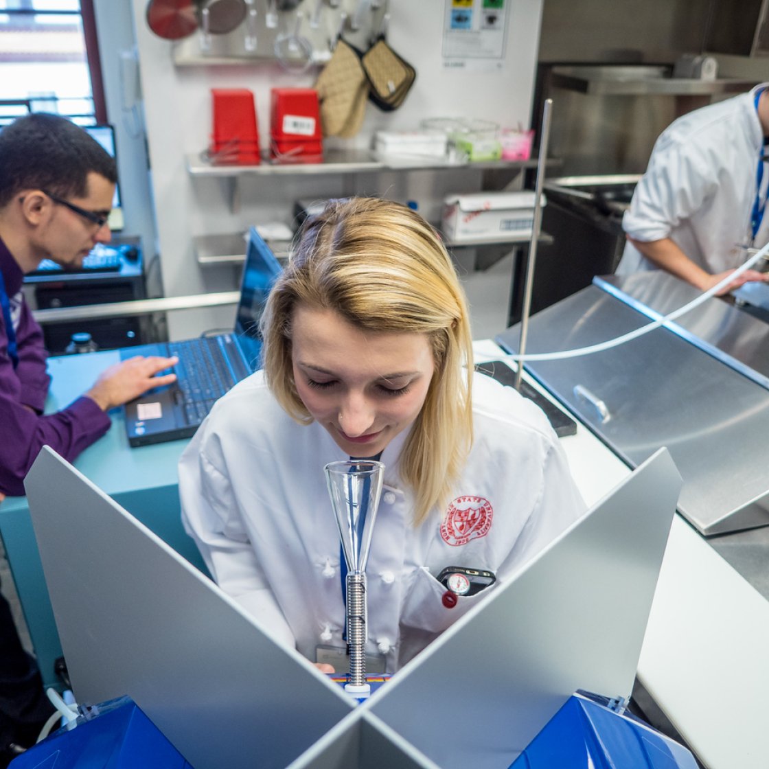 Students in a food lab using equipment.