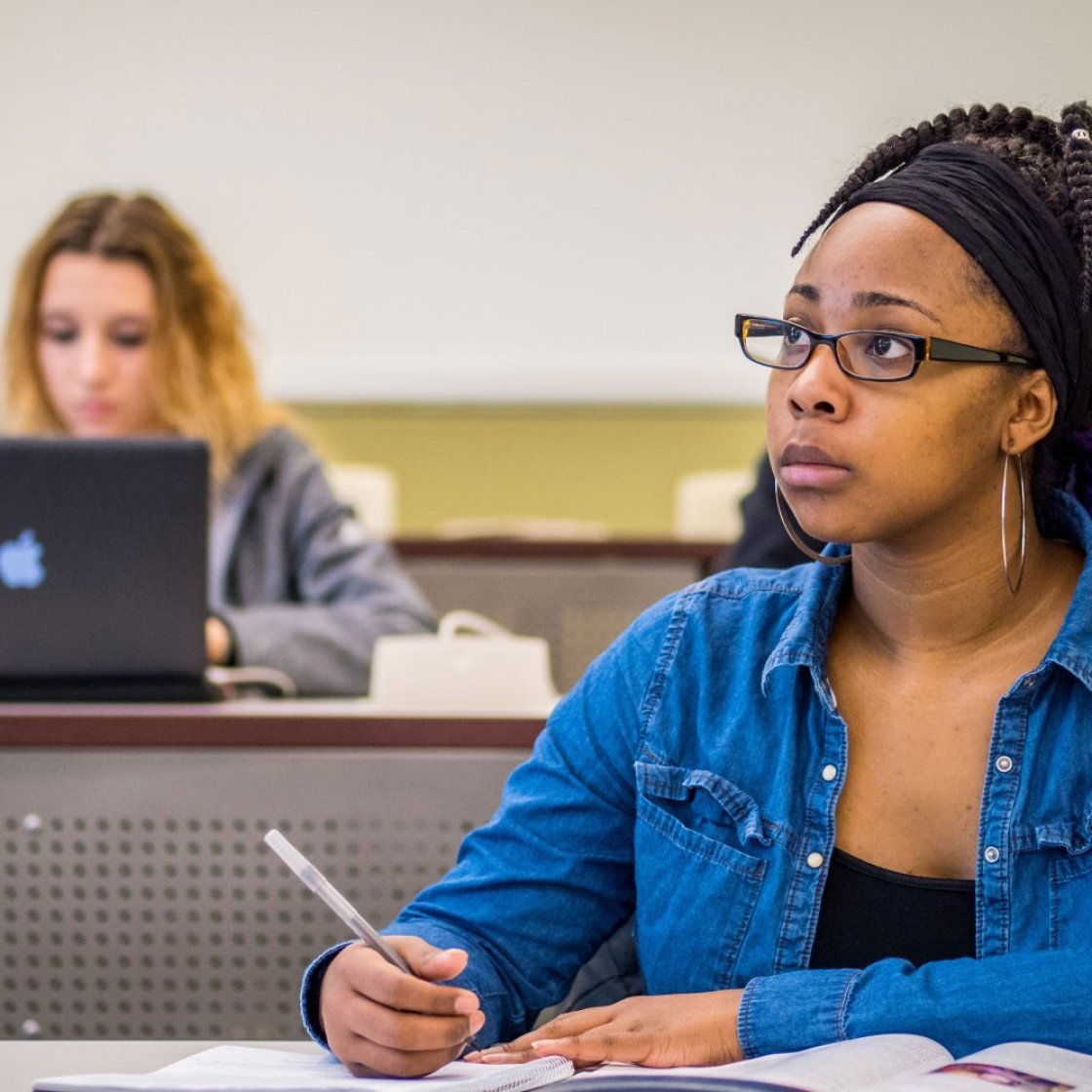 Student wearing glasses, taking notes in class