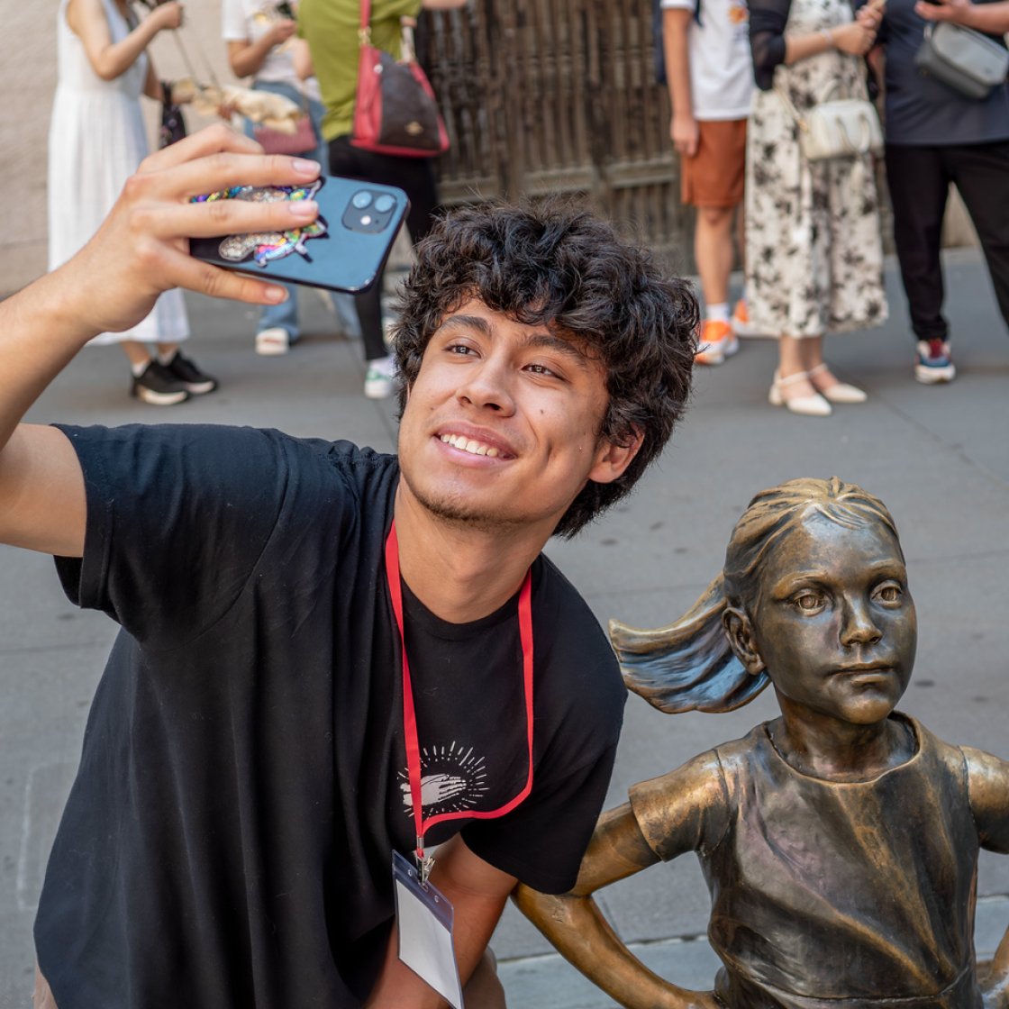 Student taking a selfie with a small statue.