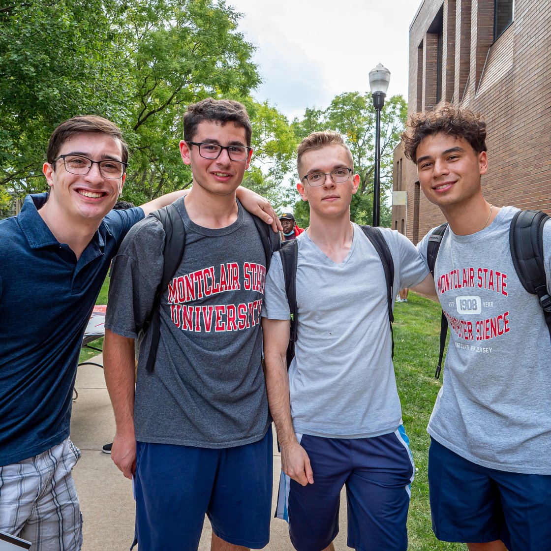 Four male students posing together outside smiling.