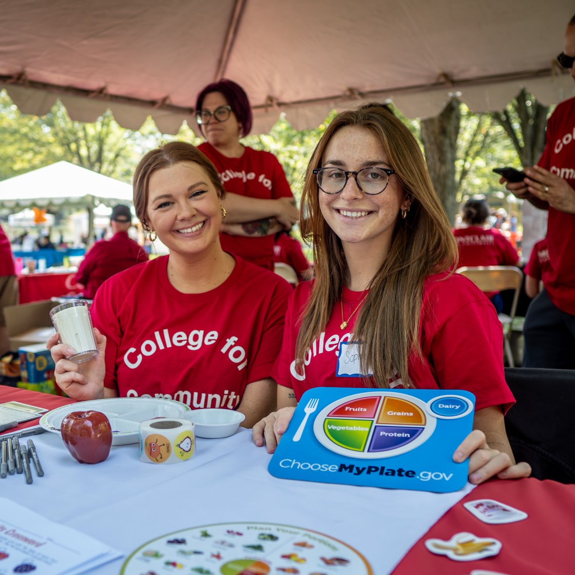 Two students are at a Health Wellness Village smiling with a picture of a plate with healthy portions.