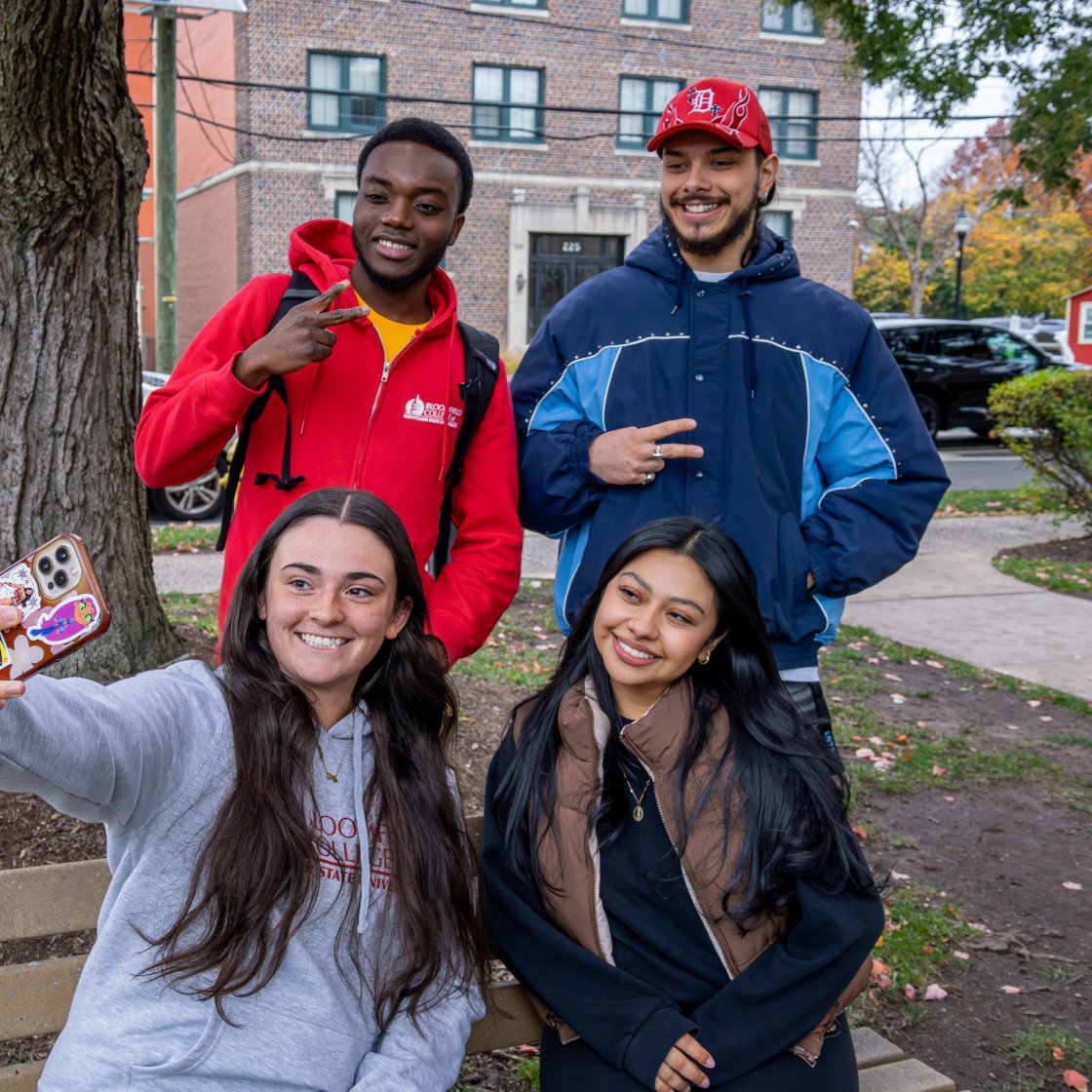 Four students are taking a selfie on campus.