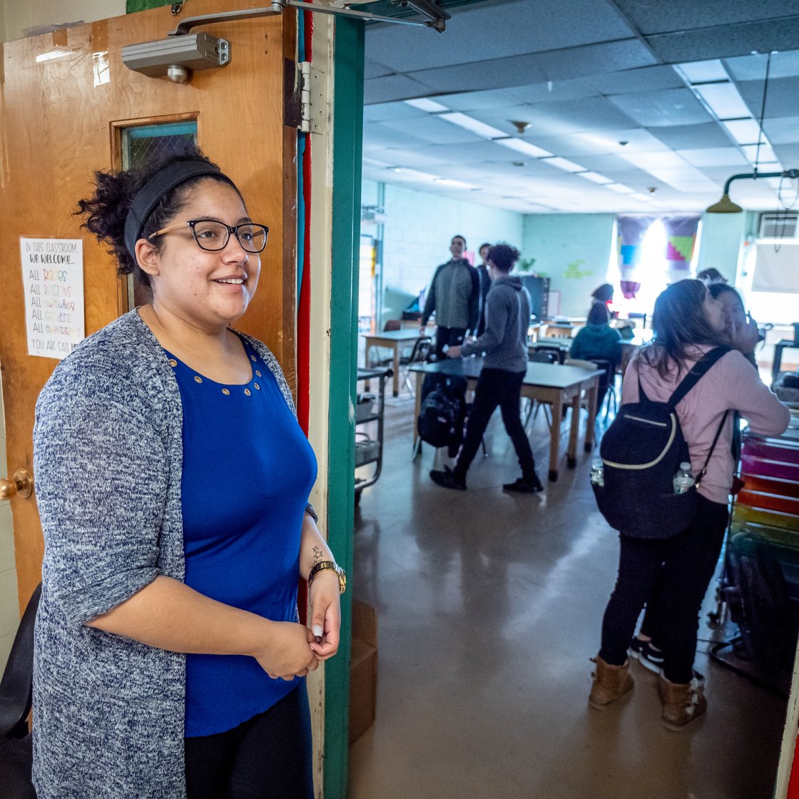 Woman standing outside a classroom with students inside.