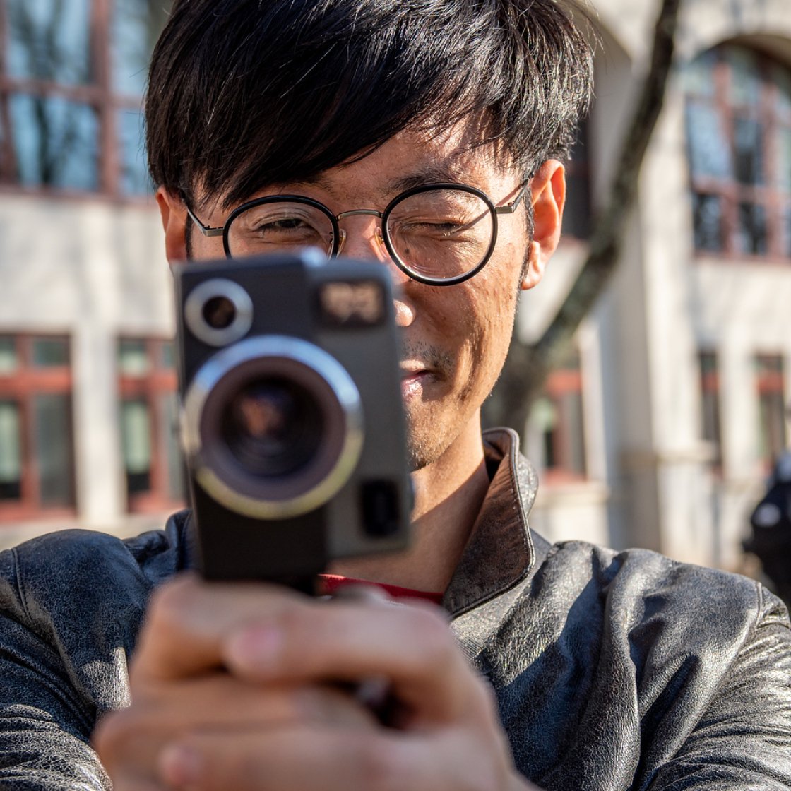 Student using a camera squinting one eye.
