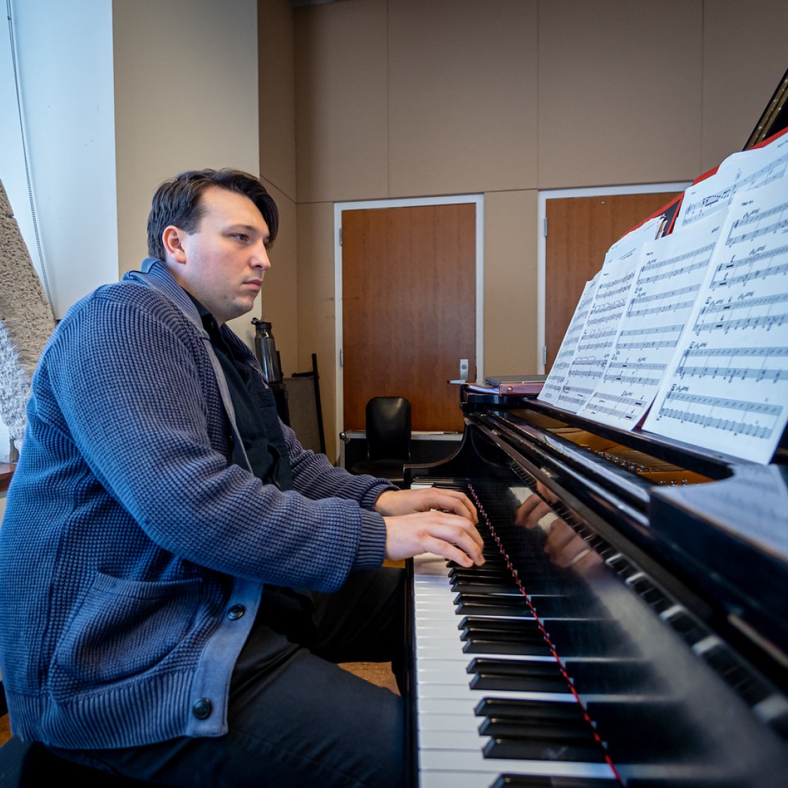 Student playing the piano with a song sheet in front of them.