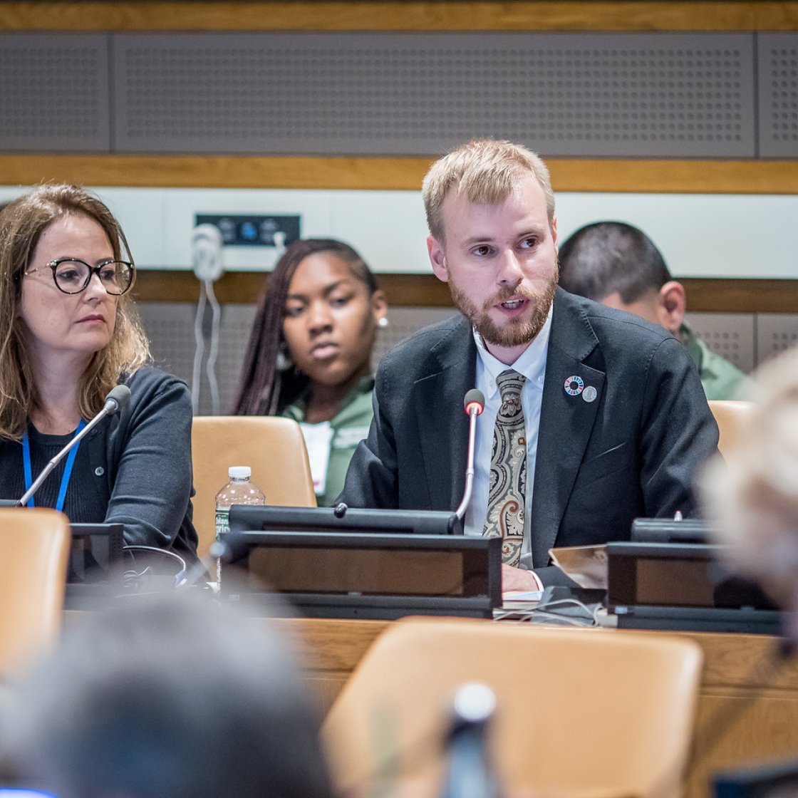 Man speaking wearing a suit at a UN event.