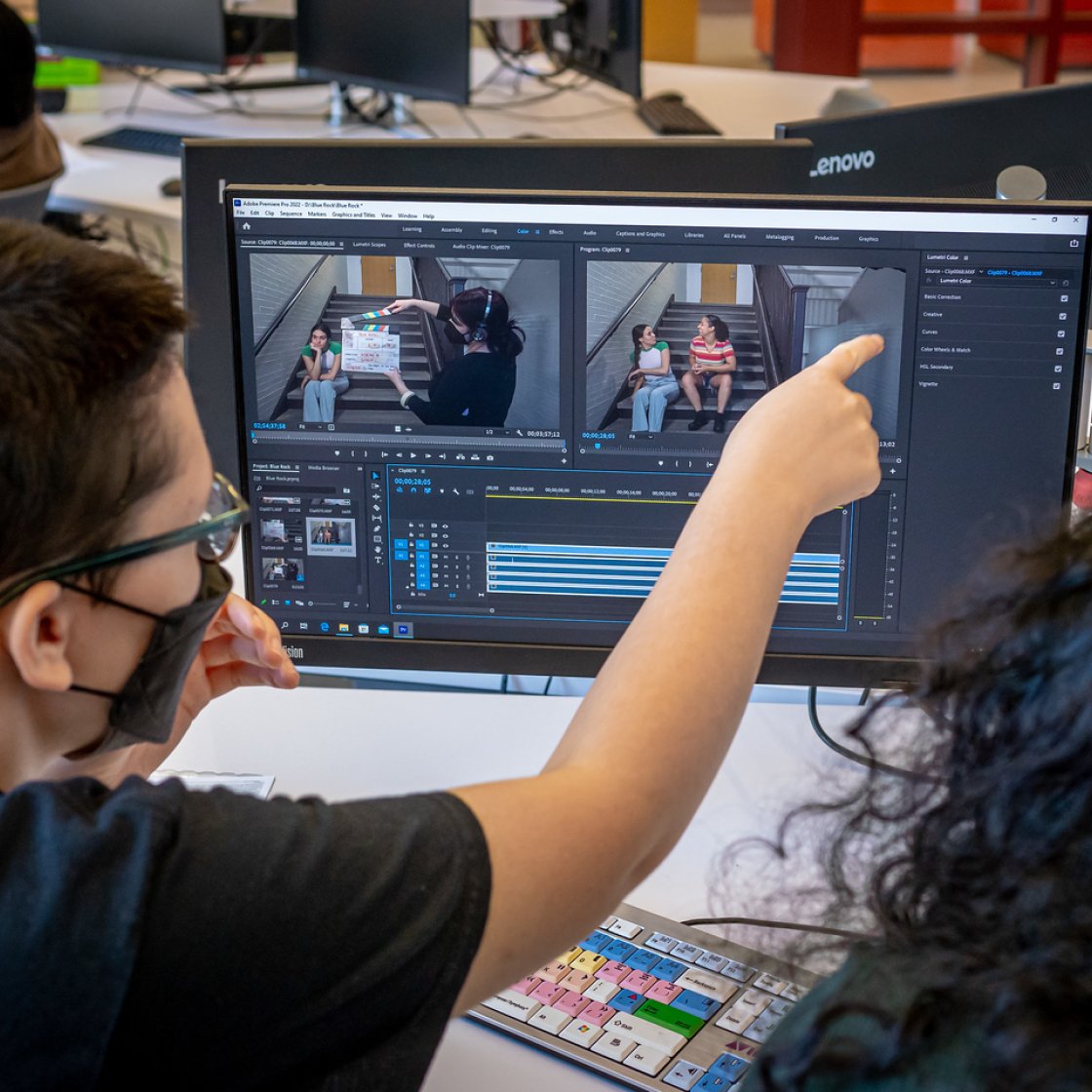 Student is pointing at a computer screen while video software is being displayed.