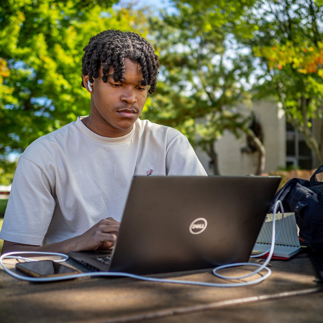 Student working on their laptop outside near Montclair State Univerisity quad.