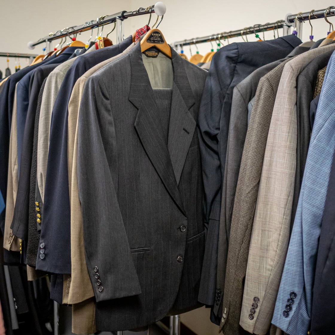 Suits hung on a hangers on a clothing rack.