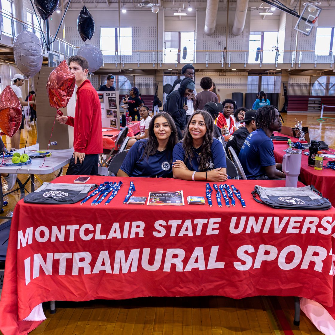 Two students set at a table with Intramural Sports Event over the tablecloth.