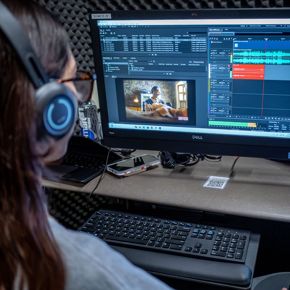 student wearing headphones with video editing software open on screen