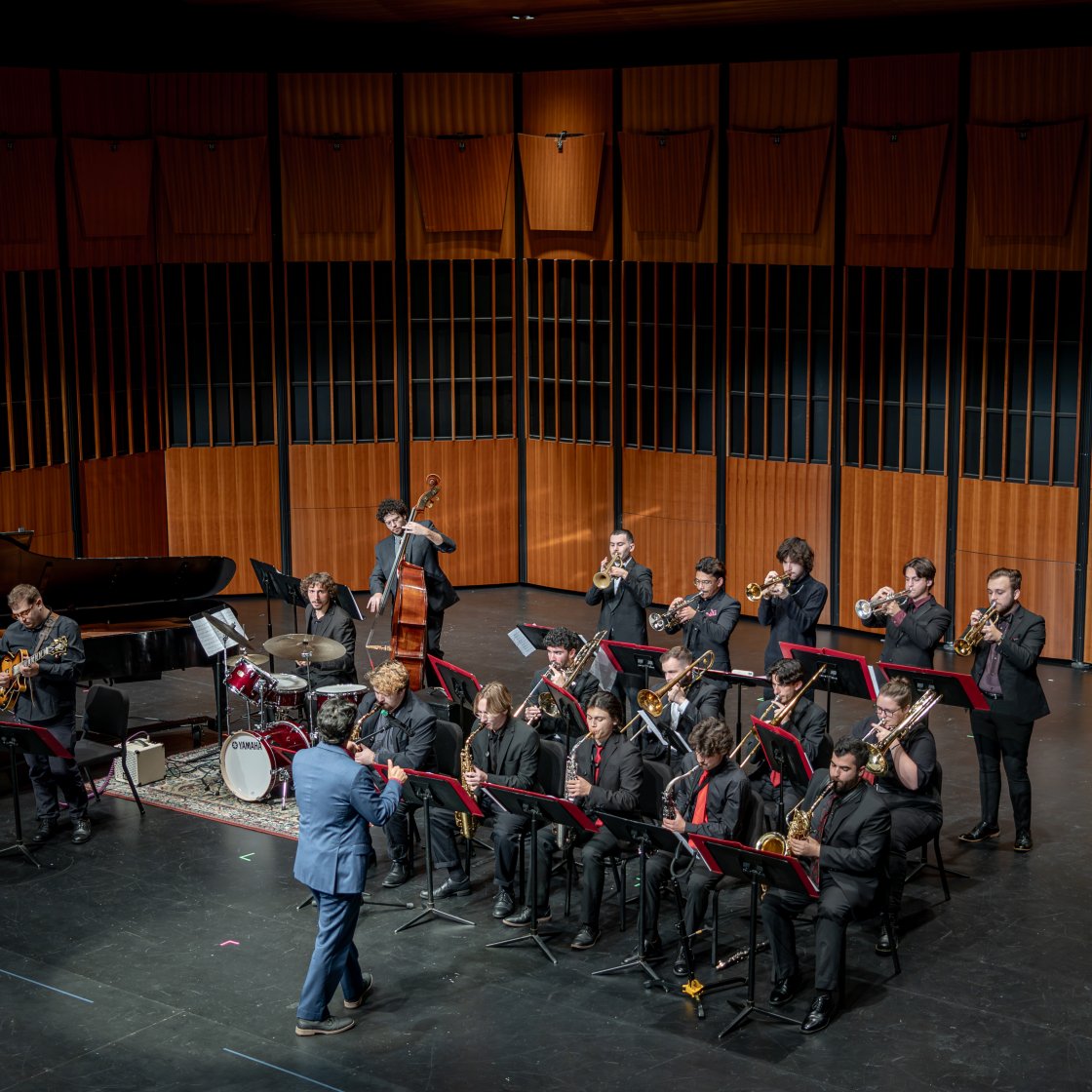 Group of students performing with instruments on stage.