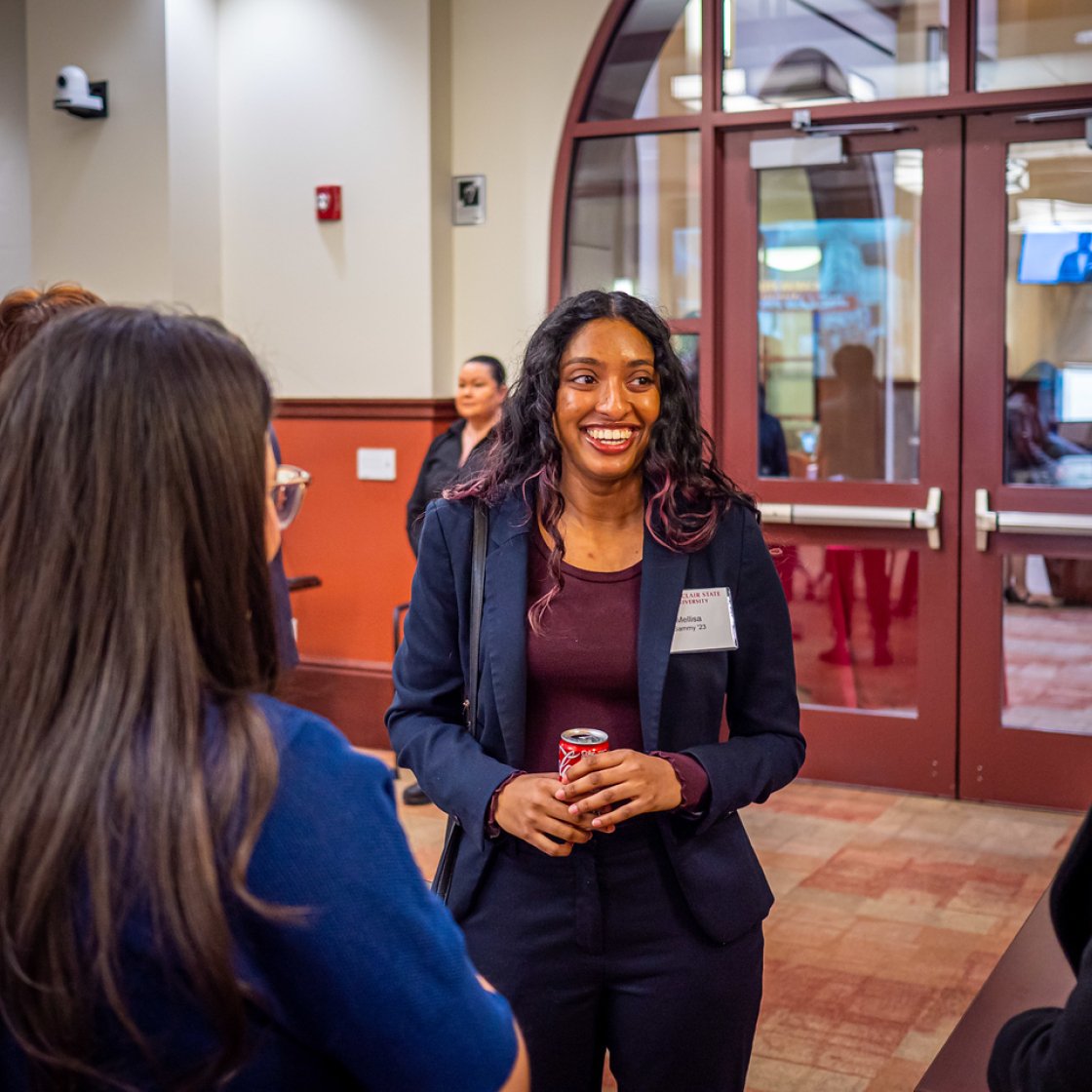Female student at a Networking Event conversing with others.