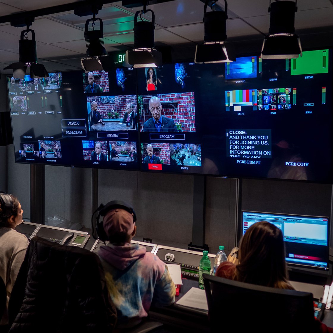 students in broadcasting studio with monitors above