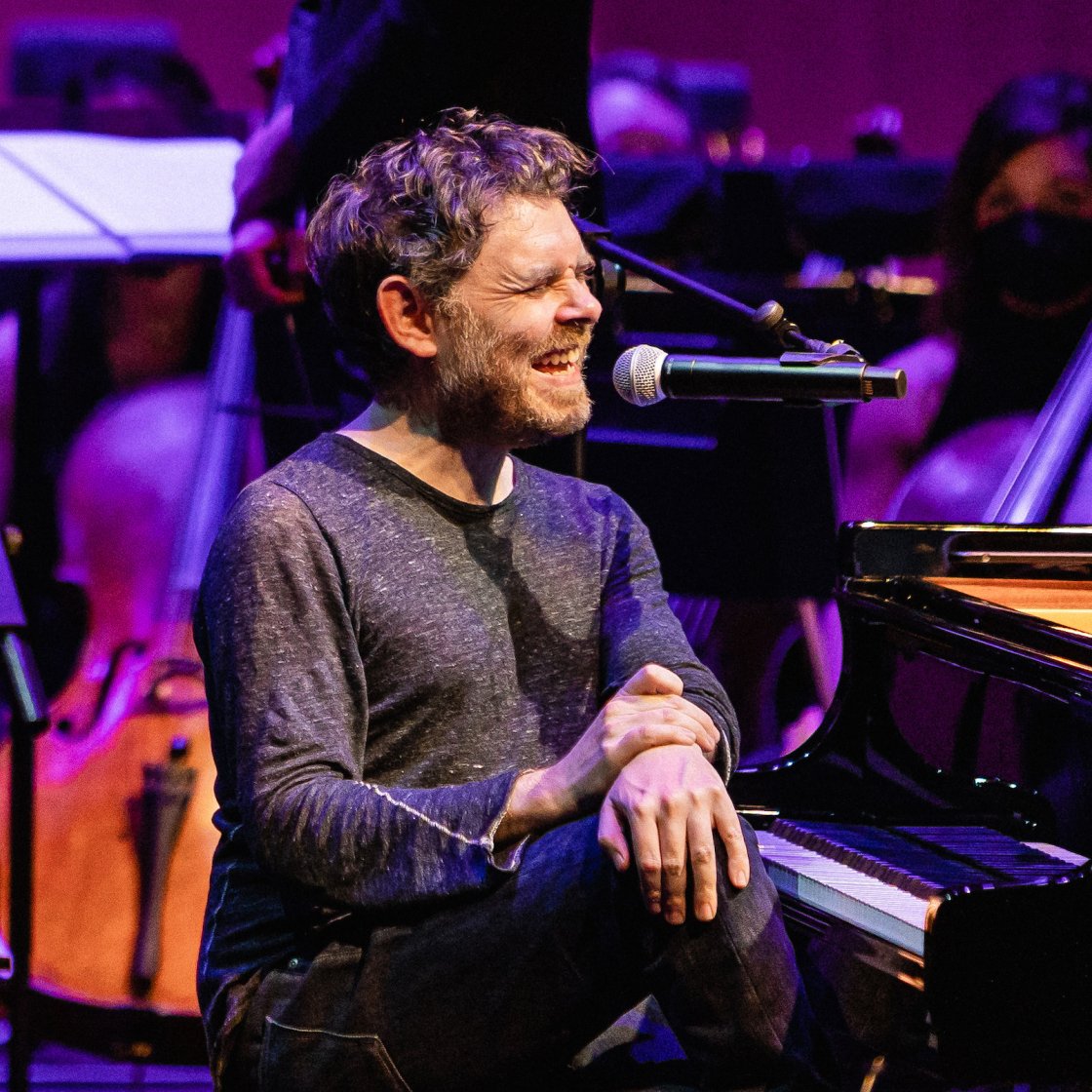 Gabriel Kahane on stage singing into microphone
