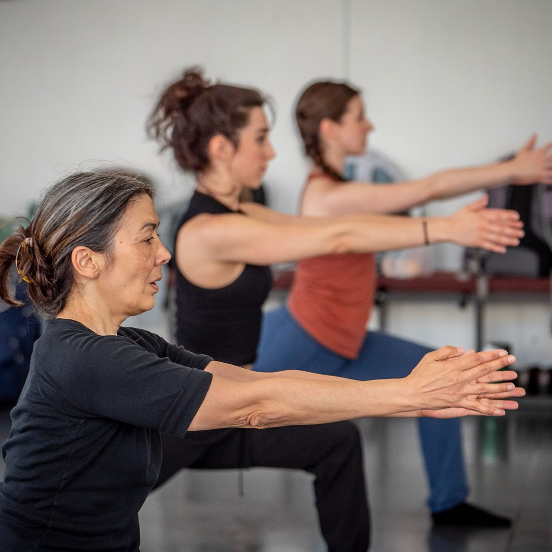 Dance students in class with arms extended forward