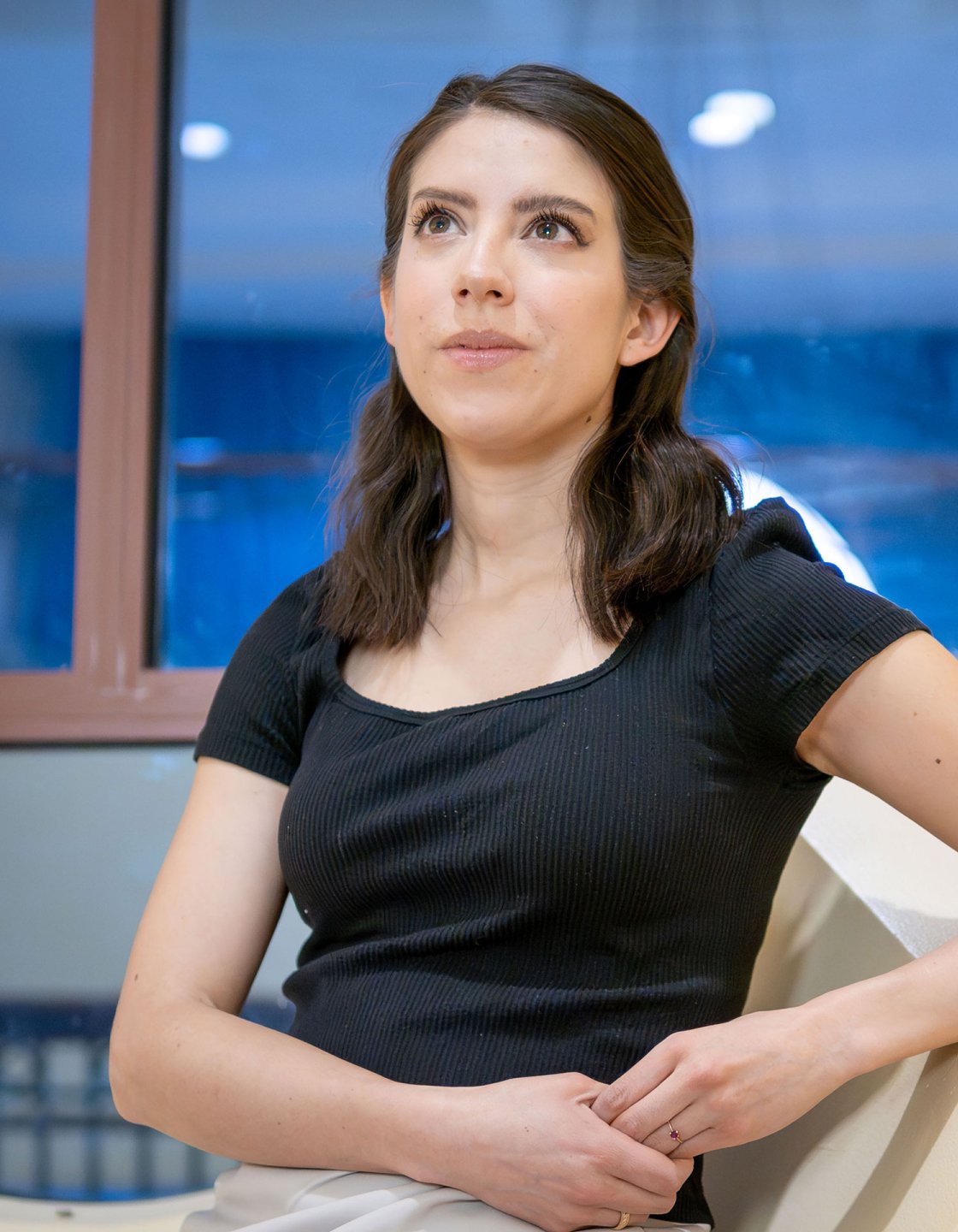 Andrea Uguna looks up while seated near a window.