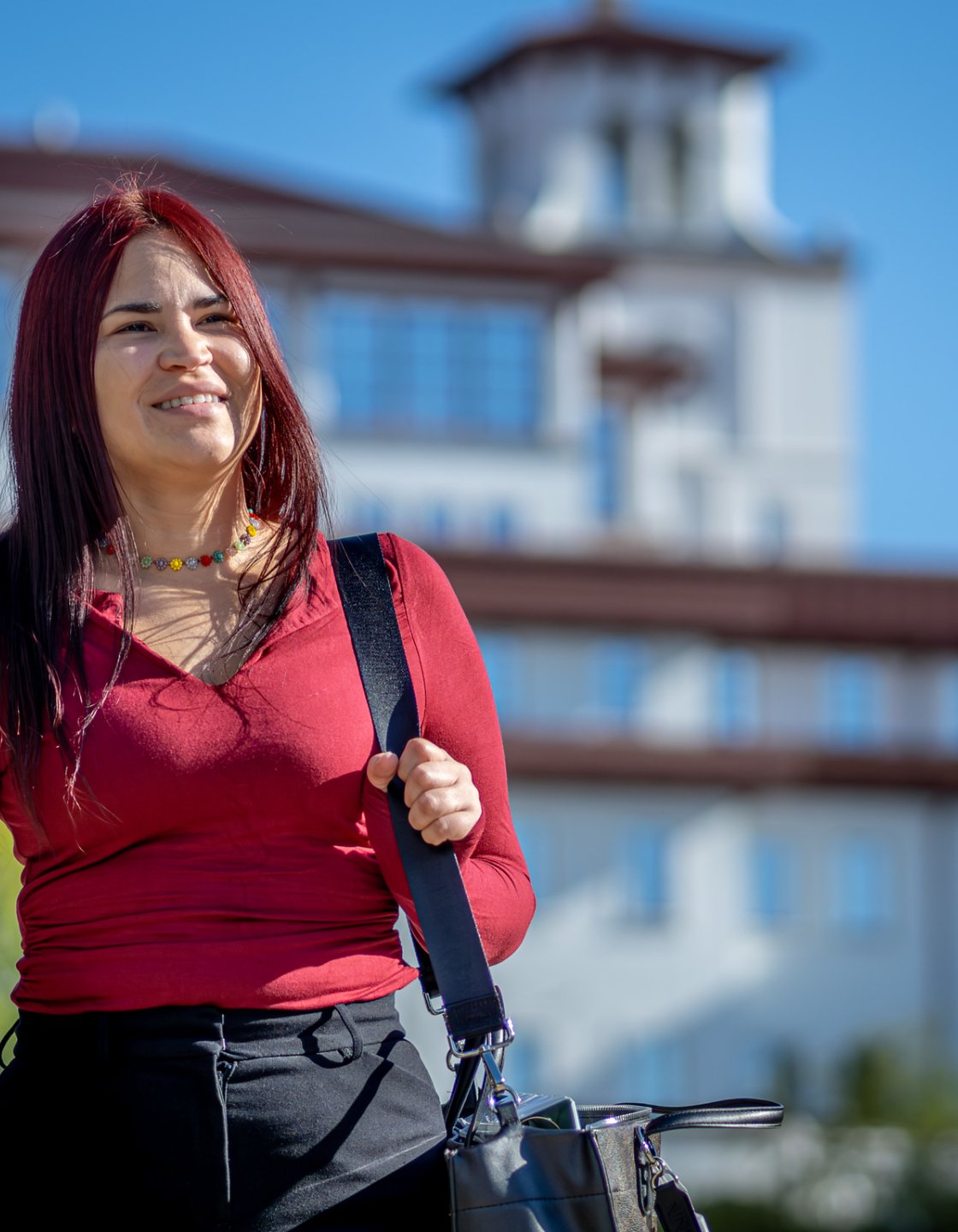 Oscaterin Bautista walks across campus carrying a bag, with a Montclair academic building in the background.