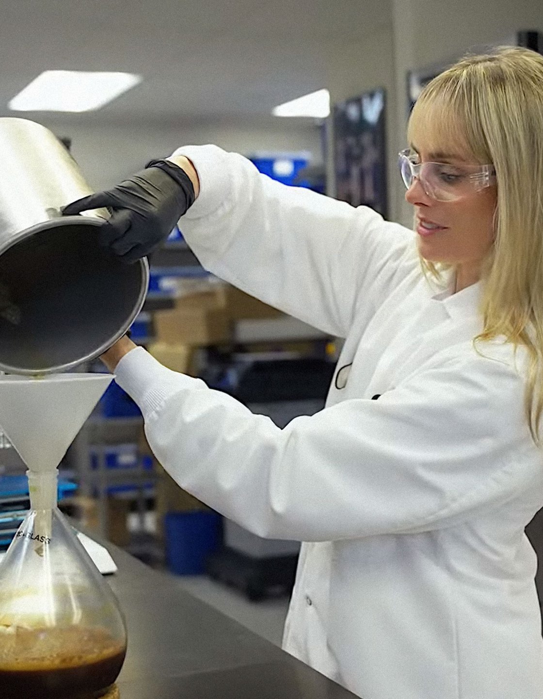 Student pouring liquid into a lab flask.