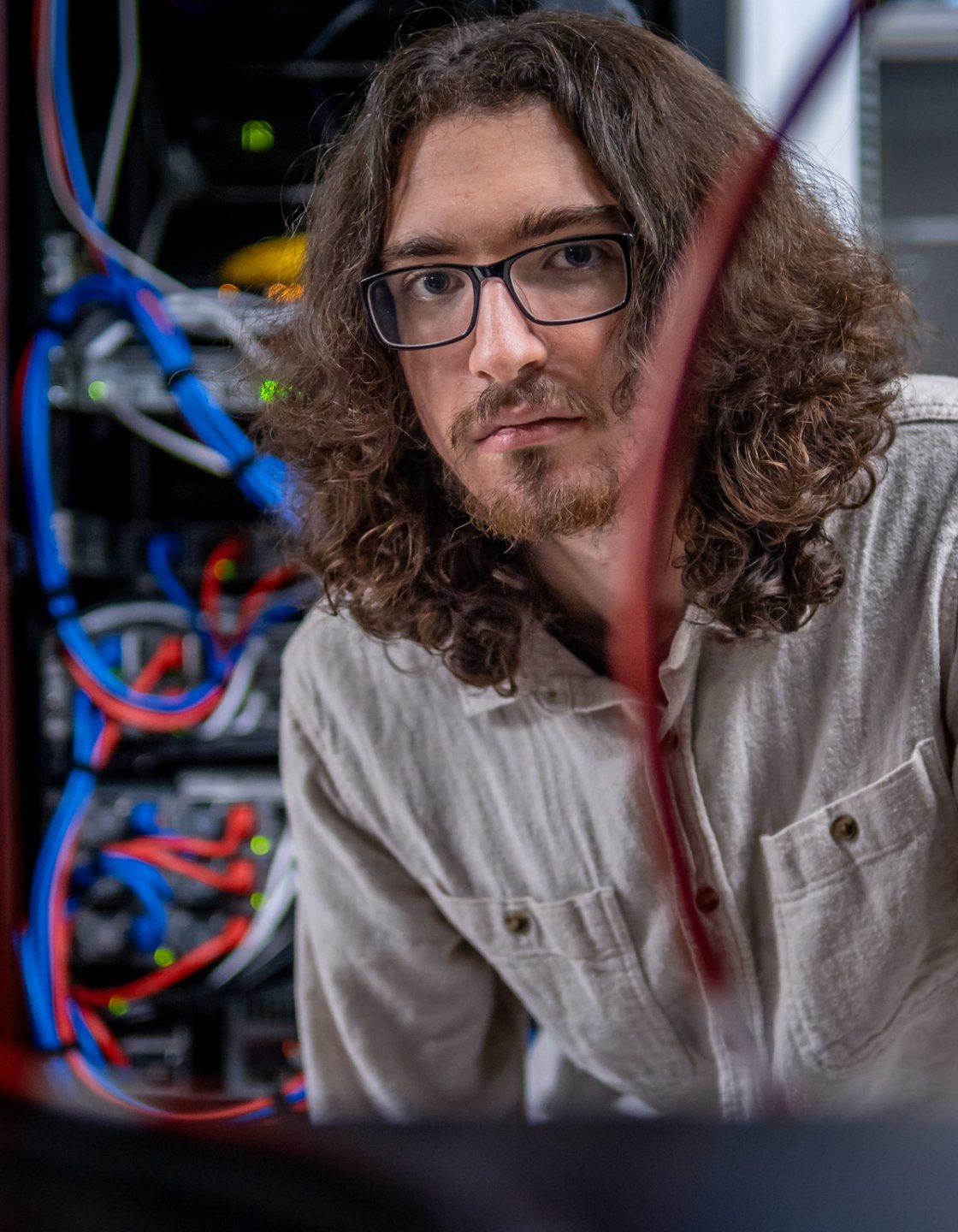Joseph David Quinn‑Vitabile works in a server room, surrounded by network cables and equipment.