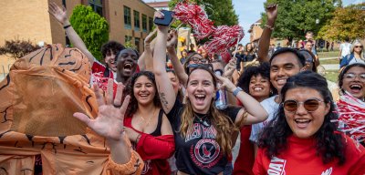 A crows of students at homecoming shouting for the camera