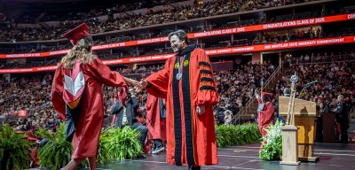 President Koppell giving a handshake to student on stage at commencement ceremony.