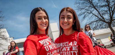 Two female students wearing red shirts smiling together.