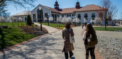 two students walking on campus in spring, various trees blooming