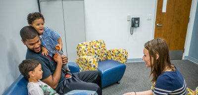 Two adults and two children are on couches in a room.
