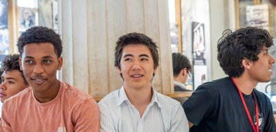 Three students are sat down smiling at a Pre College Day.