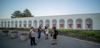 Students huddles around talking with the words Red Hawk Country behind them on a wall.