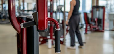 Gym machine with a man in the background working out.