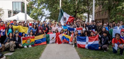 Students taking a group photo, holding up various flags of Latin America.