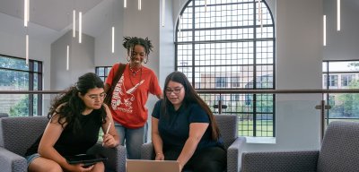 Three students working on a laptop together.