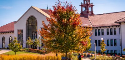 A student walks past Susan A. Cole Hall on Montclair State University’s campus as trees display colorful fall foliage.