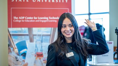Female students is smiling while raising her hand.