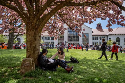 Two students sitting under a tree on Montclair State University's campus. The Open House events provide an opportunity for prospective students to experience campus life firsthand.
