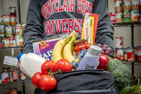 Picture of someone holding a backpack full of fruit, vegetables, and hygiene products. 