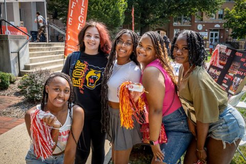 Five female students are pictured smiling close together. 