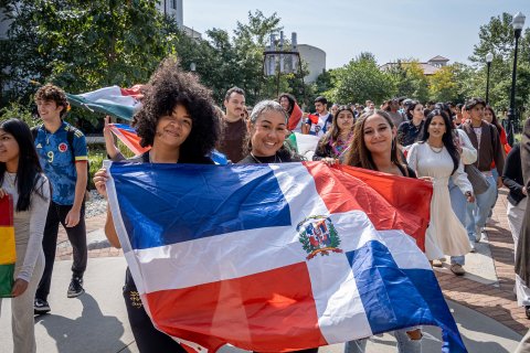 Students participating in a processional, proudly holding the flags of their respective countries during Montclair State University's flag-raising ceremony for Hispanic Heritage Month.