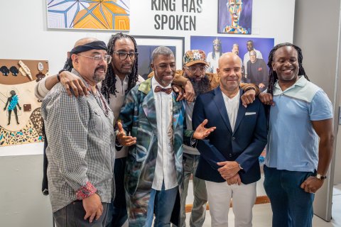 Six men are pictured posing for the camera, some are in suits while others are in dress shirts and collared shirts. 