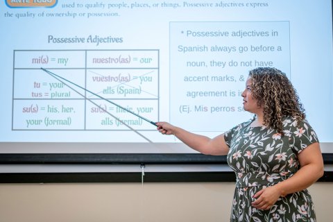 A woman points to a screen with Spanish adjectives on it.