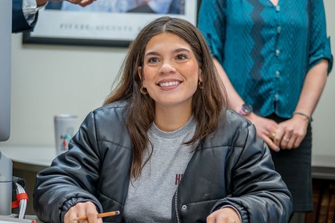 Transfer student Abigail Rodriguez sits at a desk inside a classroom with a notebook in front of her and holding a pencil.
