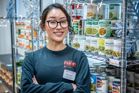 Kaori Sakae stands, arms crossed, in front of food-filled shelves at Red Hawk Pantry.