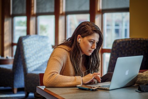 Woman working on a laptop wearing headphones