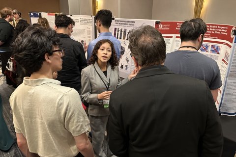 Woman pictured explaining a poster to two other gentleman. 